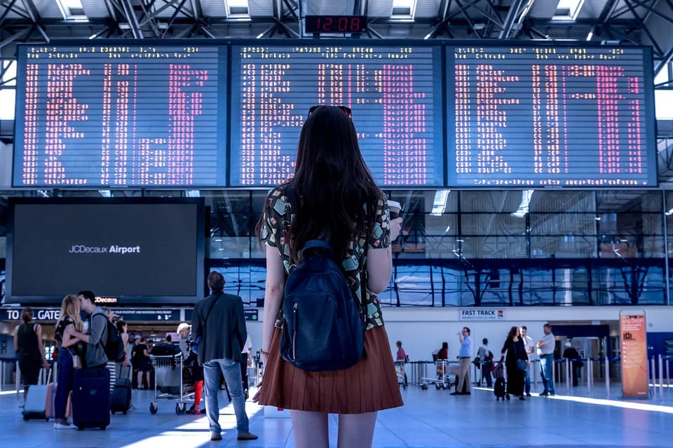 Passagierin vor der Anzeigetafel mit annullierten Flügen